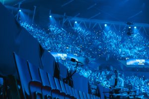 Audio-Technica stellte im Februar die gesamte Ambience-Mikrofonierung für die Intel Extreme Masters in Kattowitz. In Kooperation mit Audio-Technica entwickelte Veranstalter ESL Faceit Group ein neues Aufnahmekonzept und setzte maßgeblich auf die Mikrofone der Marke. Durch den Einsatz von 3D-, Stereo- und Richtrohrmikrofonen wurde die Arena-Atmosphäre immersiv eingefangen und im Livestream abgebildet. Um Übersprechungen der PA in der Arena auf den Ambience-Sound zu minimieren, setzte man auf ein spezielles Konzept für die Mikrofonierung. Ziel war es, ein geeignetes Setup zu finden, das bei allen zukünftigen Veranstaltungen dieser Art eingesetzt werden kann. Der Produktkatalog von Audio-Technica bot dafür die passenden Werkzeuge: Vor den Zuschauerrängen wurden die BP4025 Mikrofone aufgestellt. Durch ihre X/Y-Stereokapsel konnte ein authentisches Abbild des Publikums eingefangen werden. Ergänzend kamen die Stereo-Richtrohrmikrofone BP4029 auf Handkameras und der Spidercam zum Einsatz, um die Stimmung direkt in den Rängen wiederzugeben. Um den Zuschauern des Livestreams ein immersives Erlebnis zu bieten, wurde die Mikrofonierung auf zwei weitere Ebenen ausgeweitet. Unter der Hallendecke war mit dem BP3600 ein 3D-Mikrofon angebracht, das durch Diffusschall die Dimensionen der Arena akustisch reproduzierte. Hinzu kamen von der Decke hängende AT4050ST, die eine klangliche Brücke zwischen Diffusschall und dem Direktschall des Publikums bildeten. Dank deren M/S-Kapseln wurden die Gesamteindrücke der Zuschauer sowie des Veranstaltungsortes verstärkt und gleichzeitig PA-Übersprechungen durch das Off-Axis-Verhalten minimiert. Um eine objektive Beurteilung des Konzepts und ein detailliertes akustisches Abbild des Events vornehmen zu können, wurde in der Arena eine Testregie eigens für den Atmo-Mix eingerichtet. Auf einem dLive C1500 mit DM32 Mixrack von Allen & Heath wurden die Signale der Audio-Technica Mikrofone im Klangfeld entsprechend positioniert und aufeinander abgestimmt. Der Atmo-Mix wurde über Glasfaser an die 15 Kilometer entfernten ESL-Studios gesendet, wo dieser über eine Allen & Heath dLive S5000 mit anderen Signalen für den finalen Broadcast-Mix für den Livestream vereint wurde. https://www.audio-technica.com/de-de/ Intel Extreme Masters setzten auf Audio-Technica Mikrofone (Fotos: Audio-Technica Deutschland)